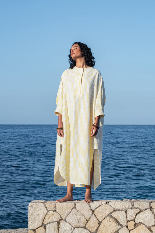 WE-AR4 model standing on a rock ledge with ocean in the background wearing the Oversize Kaftan